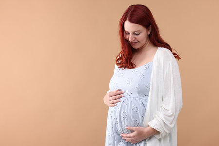 Beautiful pregnant woman on beige background, space for textの写真素材