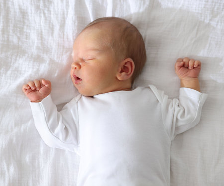 Cute newborn baby sleeping on bed, top view