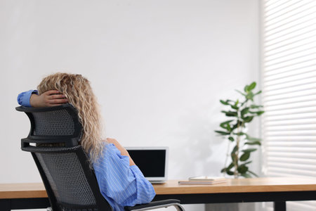 Woman sitting at workplace in office, back viewの写真素材