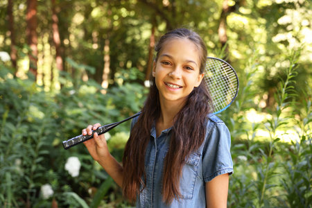 Portrait of smiling little girl with badminton racket in parkの写真素材