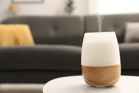 Modern aroma lamp on white table indoors. Space for text