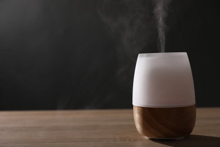 Modern aroma lamp on wooden table indoors. Space for textの写真素材