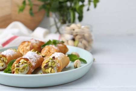 Delicious cannoli with nuts and mint on white table, closeup. Space for text