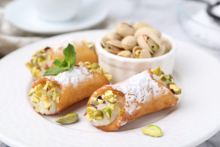Delicious cannoli with cheese, pistachios, powdered sugar and mint on table, closeupの写真素材
