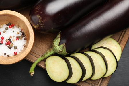 Fresh eggplants and spices on black wooden table, flat layの写真素材