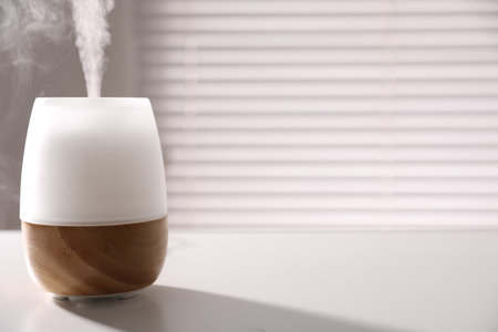 One stylish aroma lamp on white table indoors, closeup. Space for text