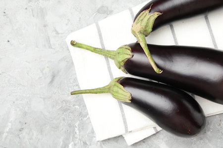 Fresh eggplants on gray textured table, top view. Space for textの写真素材