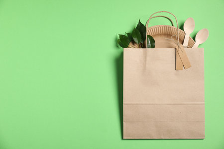 Different eco friendly packaging, tableware and leaves on light green background, top view. Space for textの写真素材