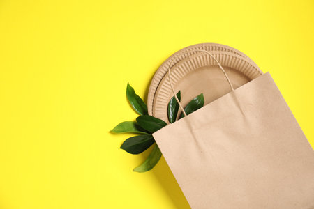 Different eco friendly packaging and leaves on yellow background, flat lay. Space for textの写真素材