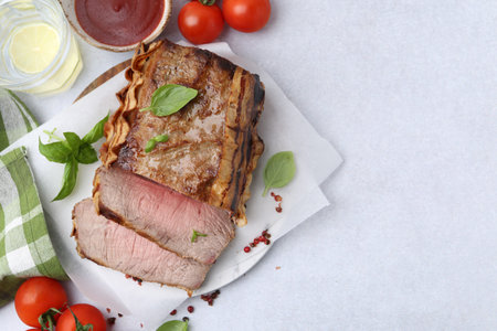 Delicious baked beef meat, tomatoes, spices and water with lime on light table, flat lay. Space for textの写真素材