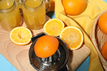 Squeezer, oranges and fresh juice on blue wooden table, closeup