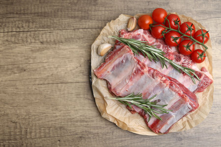 Fresh raw beef ribs, tomatoes and spices on wooden table, top view. Space for textの写真素材