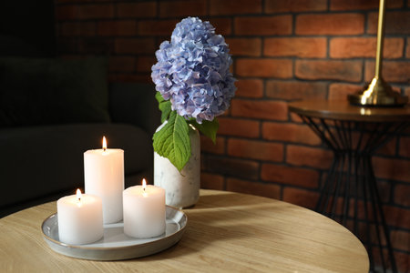 Burning candles and hydrangea flowers on wooden table at home. Space for textの写真素材