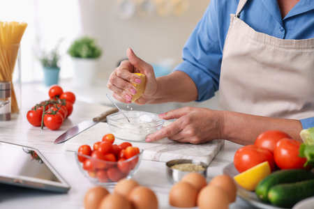 Senior woman cooking at white marble table in kitchen, closeupの写真素材