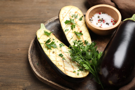 Halves of fresh eggplant, whole one, spices and parsley on wooden table, closeupの写真素材