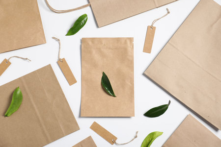 Different eco friendly packaging and leaves on white background, flat layの写真素材