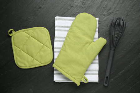 Green oven glove, towel, potholder on dark textured table, flat layの写真素材