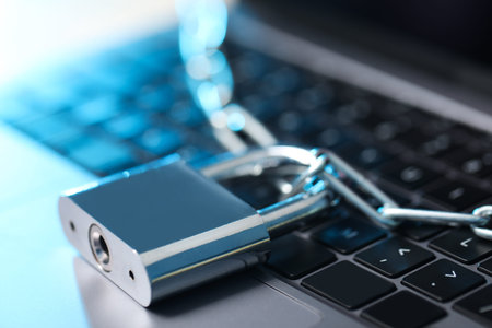 Cyber safety. Metal padlock with chain on laptop, closeup