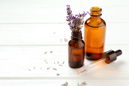 Lavender essential oil and flowers on white wooden table, closeup. Space for textの写真素材