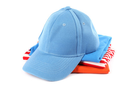 Light blue baseball cap and stack of folded t-shirts isolated on white. Mockup for designの写真素材