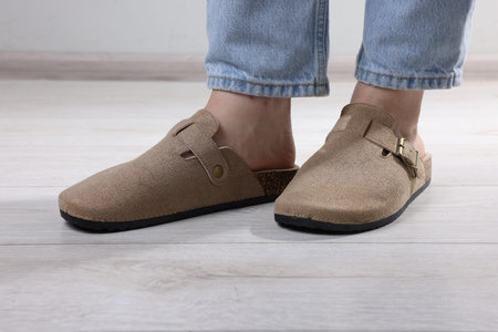 Woman in stylish beige slippers on light wooden floor, closeup