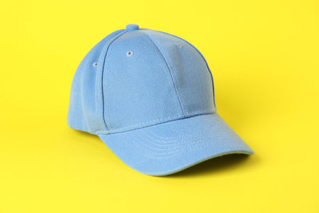 One light blue baseball cap on yellow background, closeup. Mockup for designの写真素材