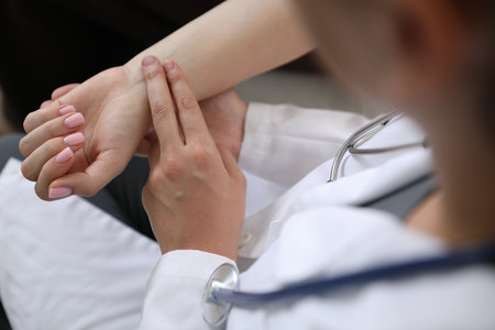 Doctor checking woman's pulse with fingers indoors, closeupの写真素材