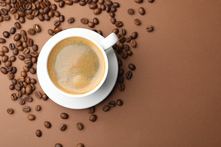 Cup of hot coffee and beans on brown background, flat lay. Space for textの写真素材