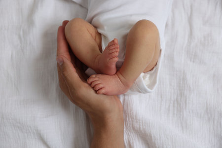 Father with his cute newborn baby on bed, top view