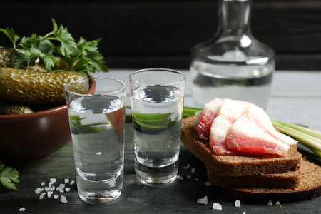 Cold vodka with snacks on wooden tableの写真素材