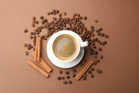 Cup of hot coffee, cinnamon and beans on brown background, flat layの写真素材