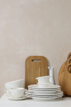 Different clean white dishware and wooden cutting boards on counter in kitchen, space for textの写真素材