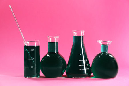 Laboratory glassware with green liquid on pink backgroundの写真素材