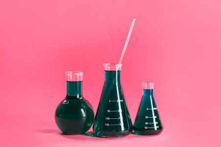 Laboratory glassware with green liquid on pink backgroundの写真素材