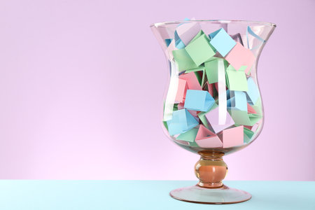 Bright paper pieces in glass jar on color background. Space for textの写真素材