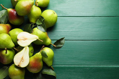 Fresh ripe pears and leaves on green wooden table, flat lay. Space for text