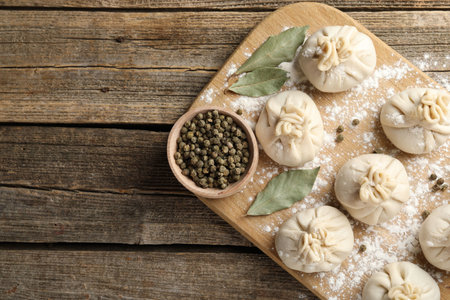 Uncooked khinkalis (dumplings) with peppercorns, flour and bay leaves on wooden table, top view.の写真素材