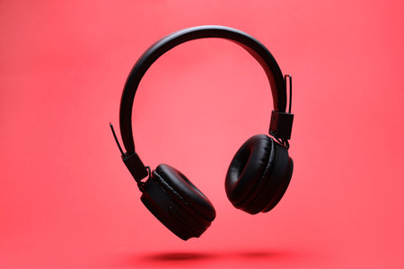 Pair of wireless headphones on coral backgroundの写真素材