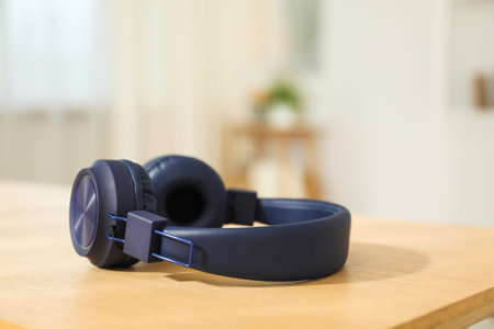 Modern wireless headphones on wooden table indoors, closeup. Space for text