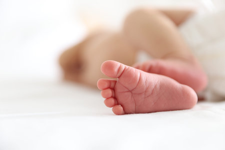 Cute newborn baby lying on bed indoors, closeup. Space for text