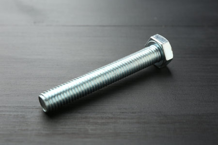 One metal bolt on dark wooden table, closeupの写真素材