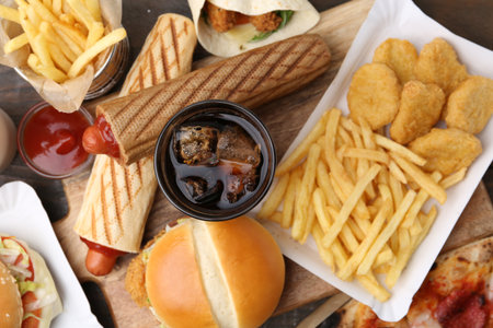 Different delicious fast food and cola on wooden table, flat layの写真素材
