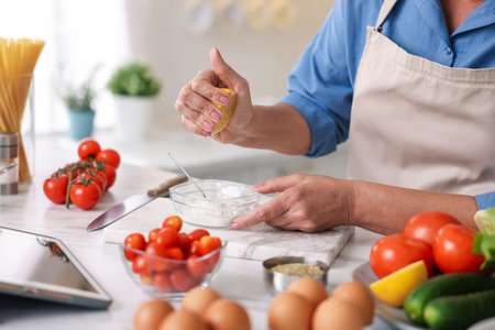 Senior woman cooking at white marble table in kitchen, closeupの写真素材