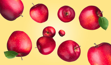 Fresh red apples swirling in air against pale orange backgroundの写真素材