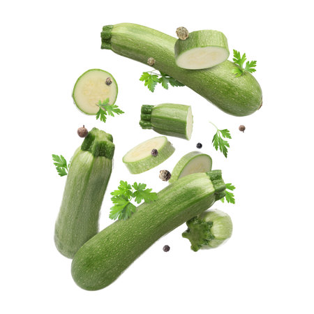 Fresh zucchinis, parsley and peppercorns falling on white backgroundの写真素材