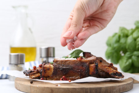 Woman salting roasted beef ribs at table, closeupの写真素材