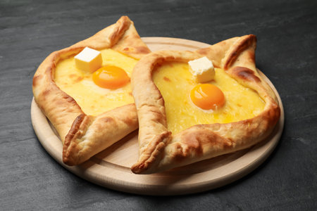 Tasty khachapuri with cheese and egg on black table, closeupの写真素材