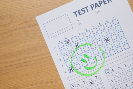 Answer sheet with drawn happy face on wooden table, top view. Student passing examの写真素材