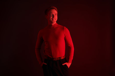 Smiling man in neon lights against dark backgroundの写真素材