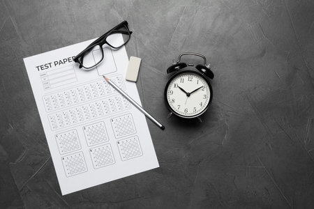 Answer sheet, alarm clock, glasses, pencil and eraser on gray textured table, flat lay. Student passing examの写真素材